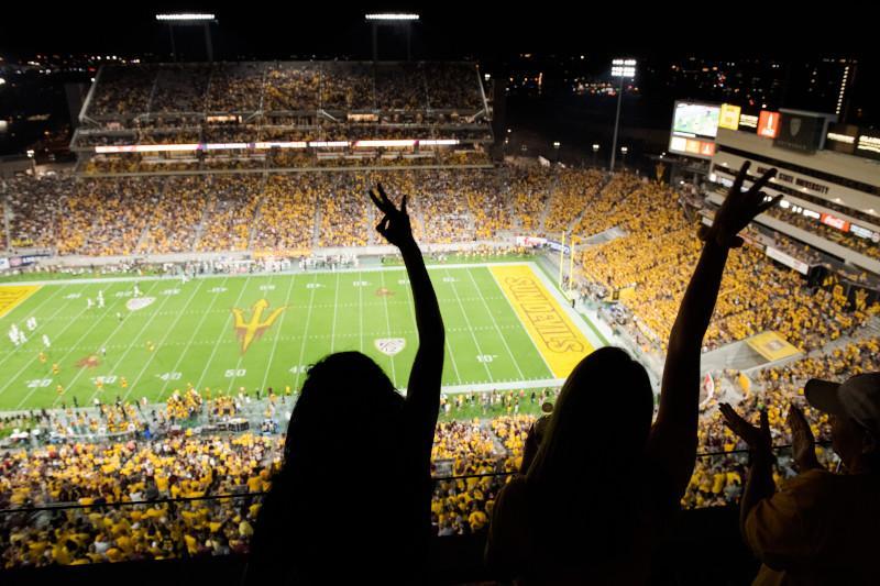 Picture of two people making pitchfork salutes at an ASU football game. / Photo by Jarod Opperman
