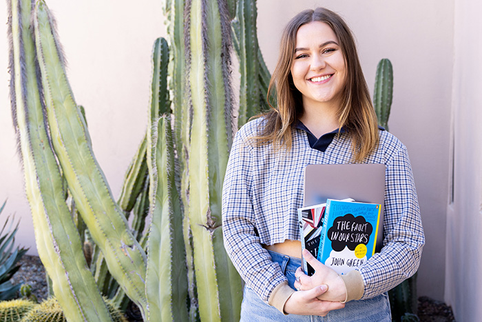 A student holding books and a computer outside the RBHL building.